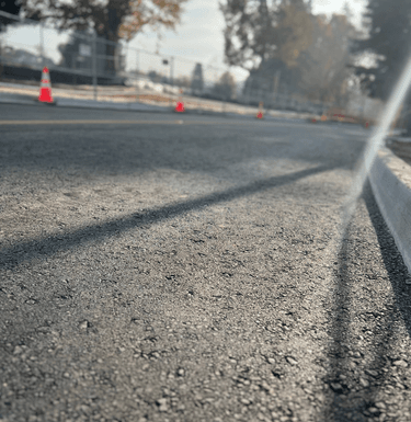 Image of street with cones lined up and trees in the background